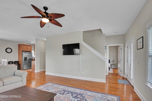 living room featuring light wood-style floors, ceiling fan, and baseboards