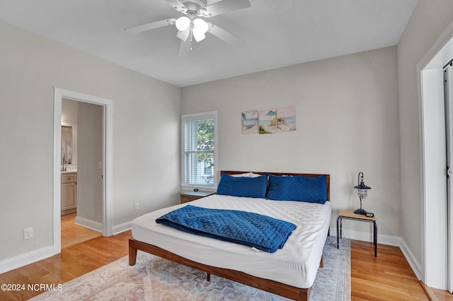 bedroom with light wood-type flooring, ceiling fan, baseboards, and ensuite bathroom