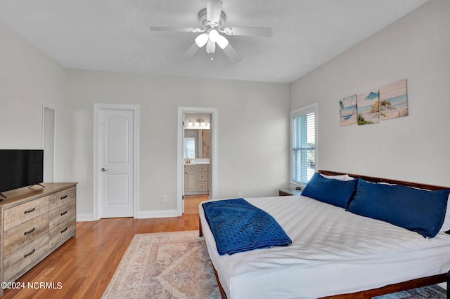 bedroom featuring ensuite bathroom, a ceiling fan, light wood-style flooring, and baseboards