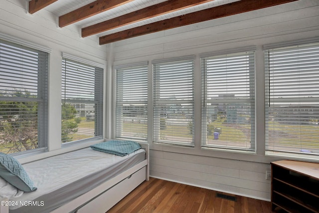 bedroom featuring beamed ceiling, wood walls, and dark wood-style flooring