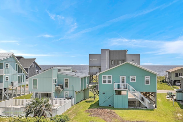 rear view of house with a water view, fence, stairs, a yard, and a residential view