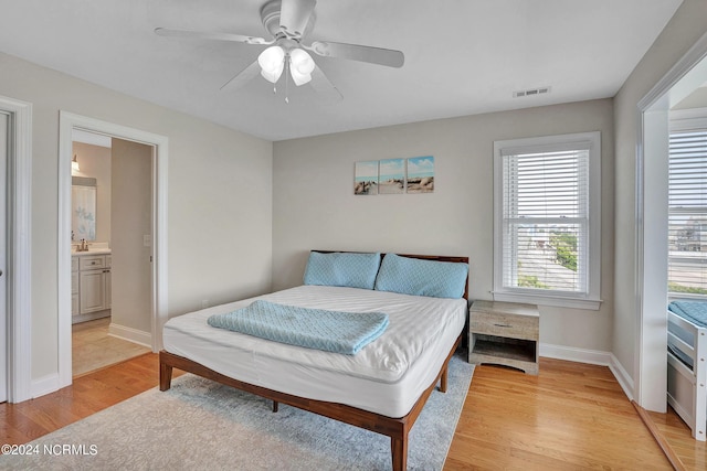 bedroom featuring ceiling fan, a sink, visible vents, baseboards, and light wood finished floors