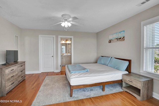 bedroom with light wood-type flooring, baseboards, visible vents, and ensuite bathroom