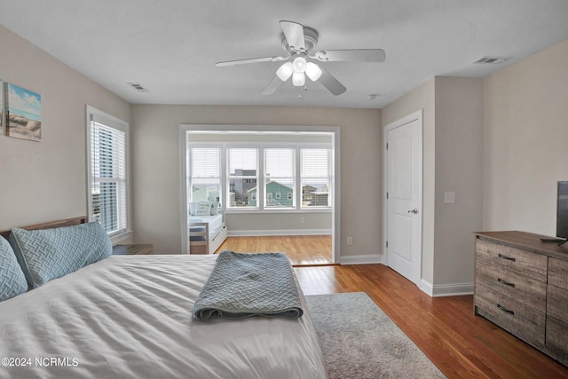 bedroom featuring ceiling fan, wood finished floors, visible vents, and baseboards