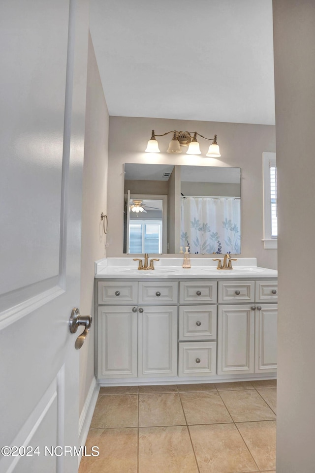 bathroom featuring tile patterned floors, a sink, a shower with shower curtain, and double vanity