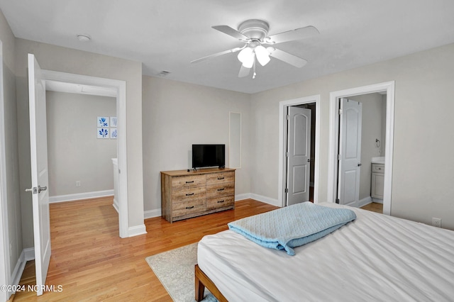 bedroom with light wood finished floors, visible vents, ensuite bathroom, a ceiling fan, and baseboards