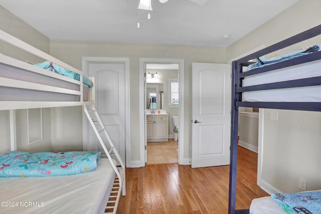 bedroom featuring light wood finished floors, ensuite bath, and baseboards