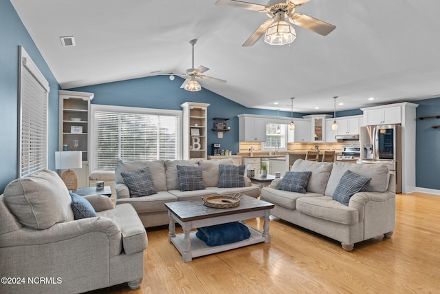 living room with ceiling fan, vaulted ceiling, light hardwood / wood-style flooring, and sink