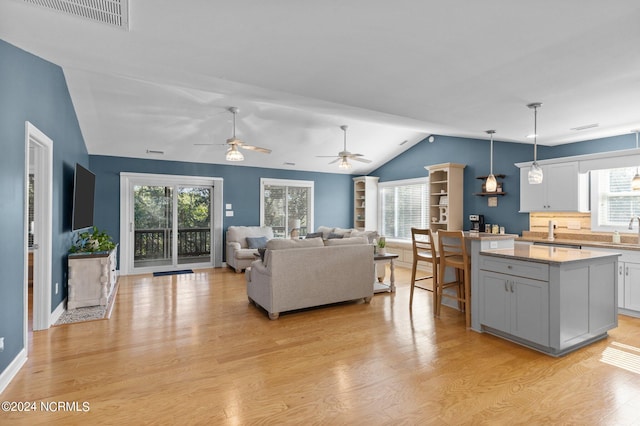 living room with ceiling fan, a wealth of natural light, light hardwood / wood-style flooring, and lofted ceiling