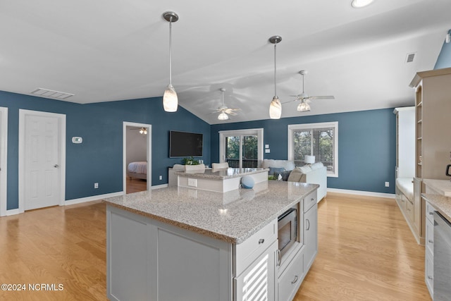 kitchen featuring ceiling fan, light wood-type flooring, hanging light fixtures, stainless steel microwave, and lofted ceiling