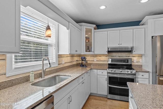 kitchen with backsplash, hanging light fixtures, light hardwood / wood-style flooring, white cabinetry, and stainless steel appliances