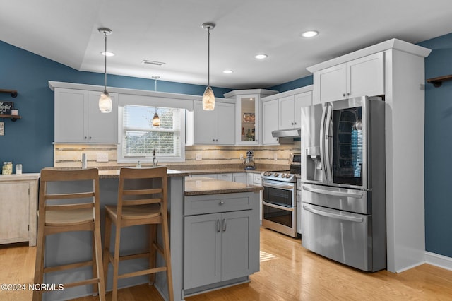 kitchen with decorative light fixtures, backsplash, appliances with stainless steel finishes, and stone counters