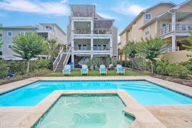 outdoor pool with stairway, an in ground hot tub, and fence