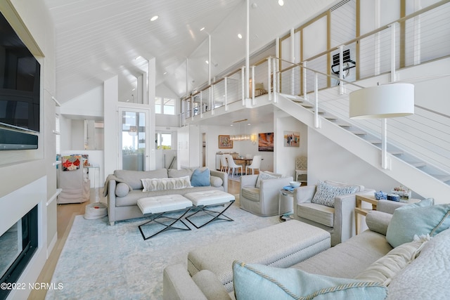 living room featuring stairs, recessed lighting, wood finished floors, and high vaulted ceiling