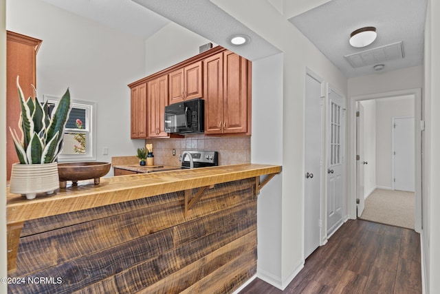 kitchen with dark colored carpet, tasteful backsplash, and stove