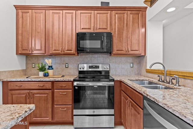 kitchen featuring stainless steel appliances, tasteful backsplash, sink, light stone countertops, and light tile patterned floors