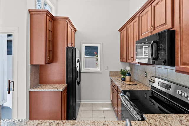 kitchen with backsplash, light stone counters, light tile patterned floors, and black appliances