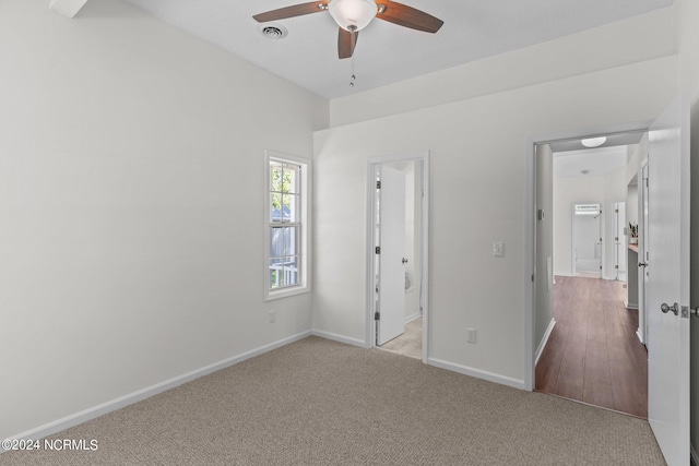 unfurnished bedroom featuring ceiling fan, light colored carpet, and ensuite bathroom