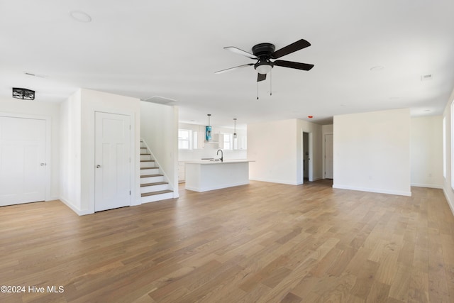 unfurnished living room featuring ceiling fan, sink, and light hardwood / wood-style flooring