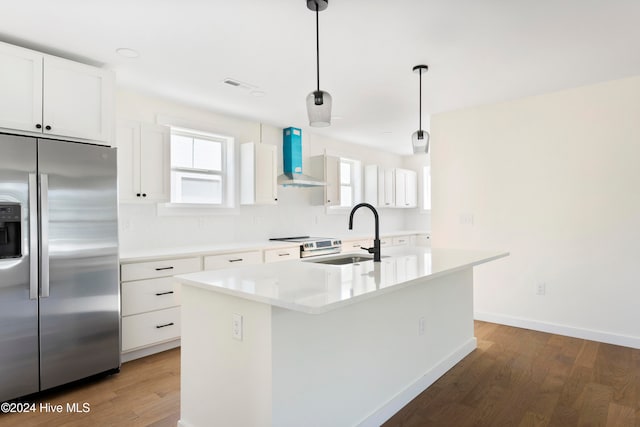 kitchen featuring a center island with sink, pendant lighting, stainless steel refrigerator with ice dispenser, sink, and wall chimney exhaust hood