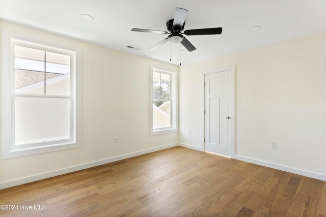 empty room with a wealth of natural light, ceiling fan, and light hardwood / wood-style flooring