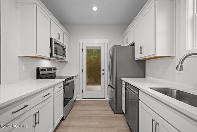 kitchen with light hardwood / wood-style flooring, appliances with stainless steel finishes, sink, and white cabinetry