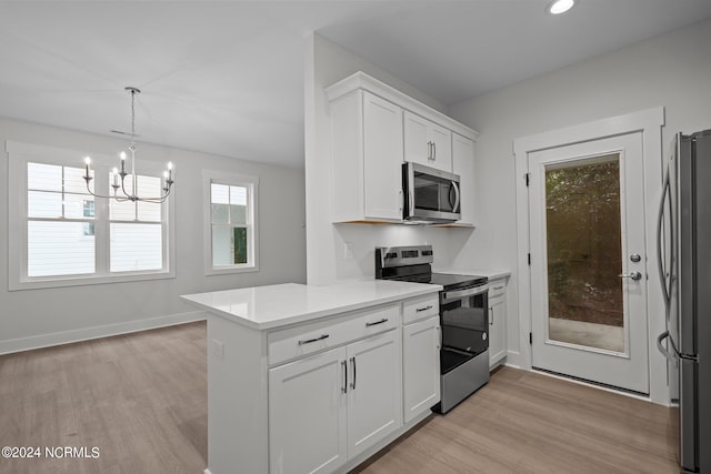 kitchen featuring light wood-type flooring, pendant lighting, stainless steel appliances, and white cabinets