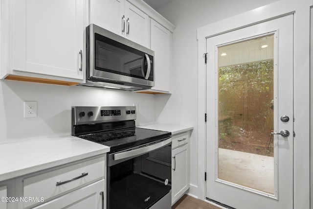 kitchen featuring white cabinetry, stainless steel appliances, and light stone counters