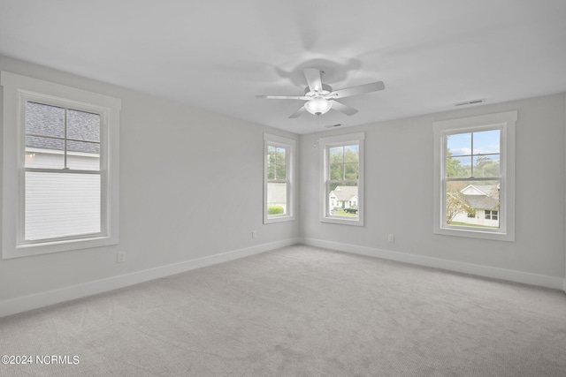 unfurnished room featuring ceiling fan, light carpet, and a wealth of natural light