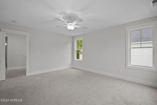 spare room featuring ceiling fan, light colored carpet, and plenty of natural light