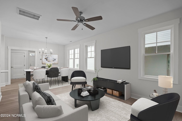 living room featuring ceiling fan with notable chandelier, a wealth of natural light, and hardwood / wood-style flooring