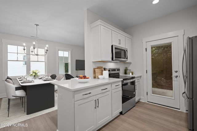 kitchen featuring light hardwood / wood-style floors, white cabinets, stainless steel appliances, an inviting chandelier, and decorative light fixtures