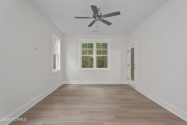 empty room with ceiling fan and light hardwood / wood-style flooring