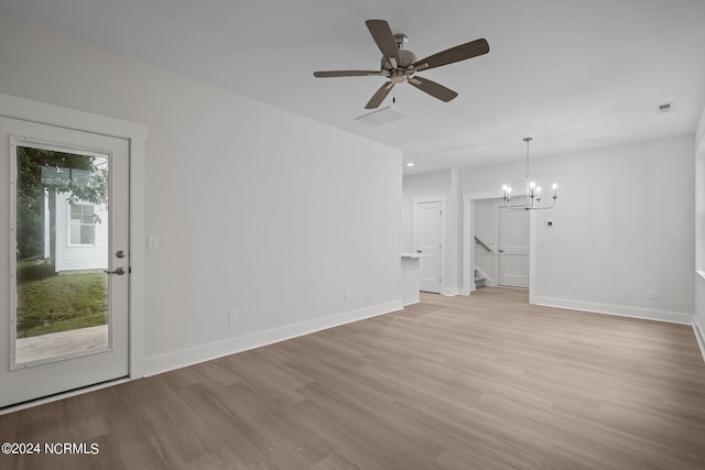 unfurnished living room with ceiling fan with notable chandelier and light hardwood / wood-style floors