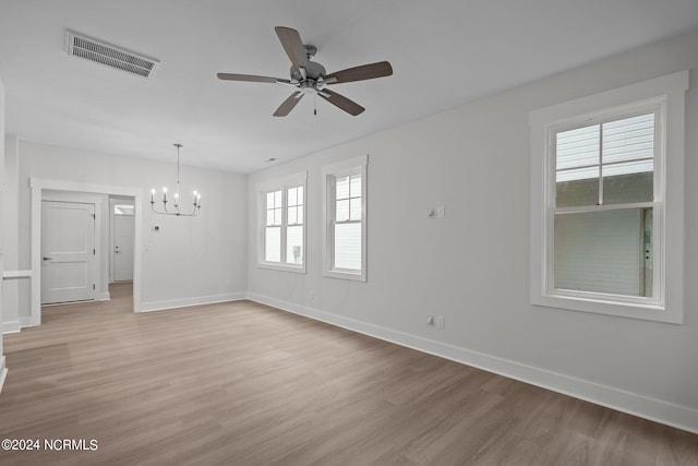 unfurnished room with ceiling fan with notable chandelier and light hardwood / wood-style flooring