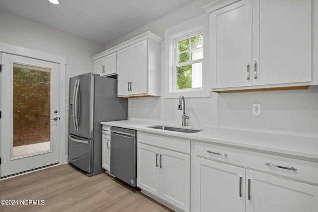 kitchen featuring white cabinets, stainless steel appliances, sink, and light hardwood / wood-style flooring