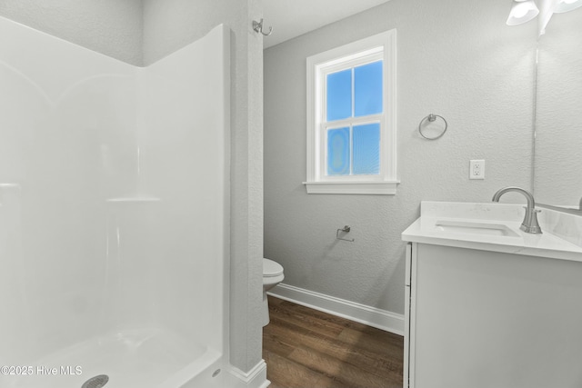 bathroom featuring vanity, hardwood / wood-style flooring, a shower, and toilet