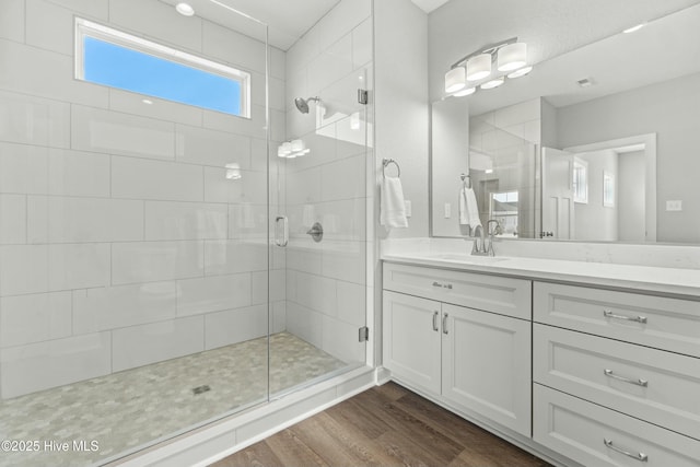 bathroom with vanity, hardwood / wood-style flooring, and a shower with door