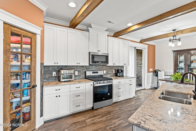 kitchen featuring white cabinets, beamed ceiling, pendant lighting, sink, and stainless steel appliances