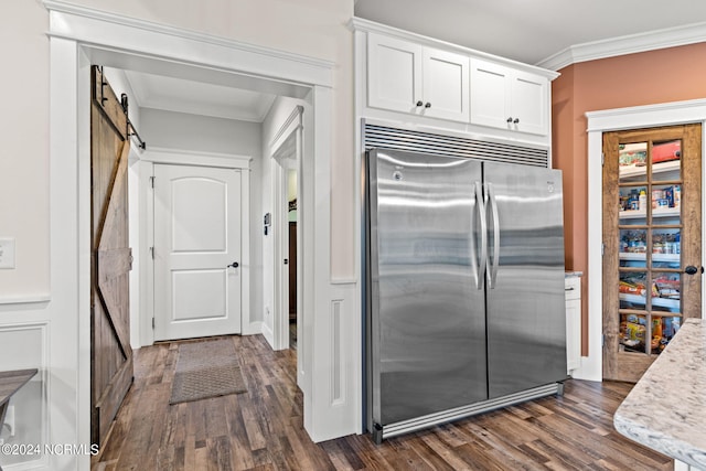 kitchen with stainless steel built in fridge, white cabinets, dark hardwood / wood-style floors, and a barn door