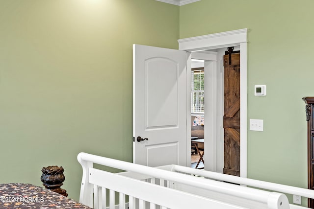 bedroom with ornamental molding and a barn door