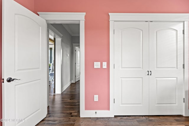 unfurnished bedroom with ornamental molding, a closet, and dark wood-type flooring