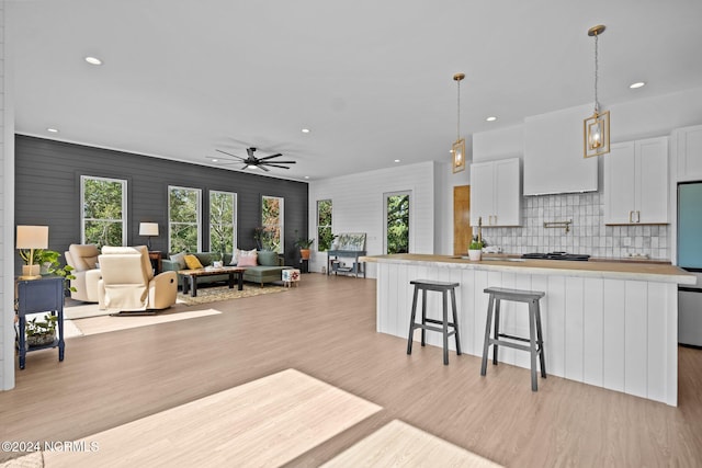 kitchen featuring a kitchen bar, appliances with stainless steel finishes, ceiling fan, light hardwood / wood-style floors, and white cabinetry