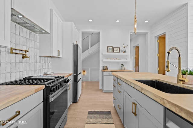 kitchen with sink, tasteful backsplash, light hardwood / wood-style flooring, decorative light fixtures, and appliances with stainless steel finishes