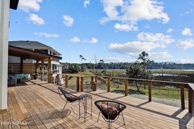 wooden deck with an outdoor living space and a water view