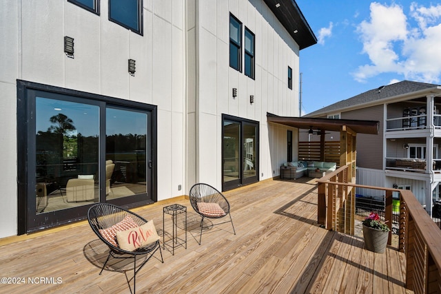 wooden terrace with ceiling fan and an outdoor hangout area