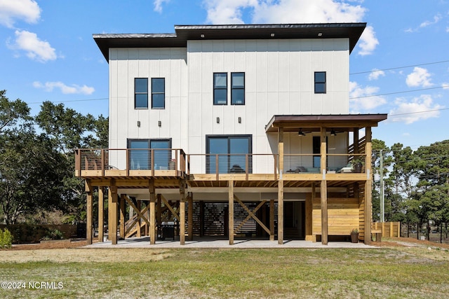 rear view of house with ceiling fan, a wooden deck, and a lawn