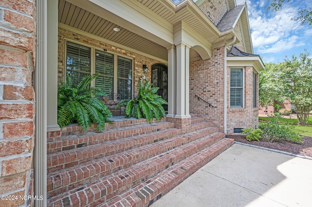 doorway to property featuring crawl space, a porch, and brick siding