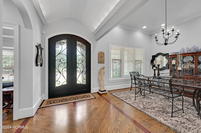 foyer featuring baseboards, arched walkways, wood finished floors, and french doors