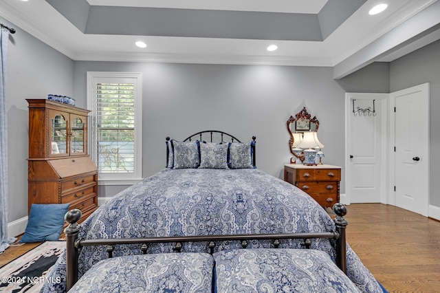 bedroom with baseboards, a tray ceiling, wood finished floors, and recessed lighting